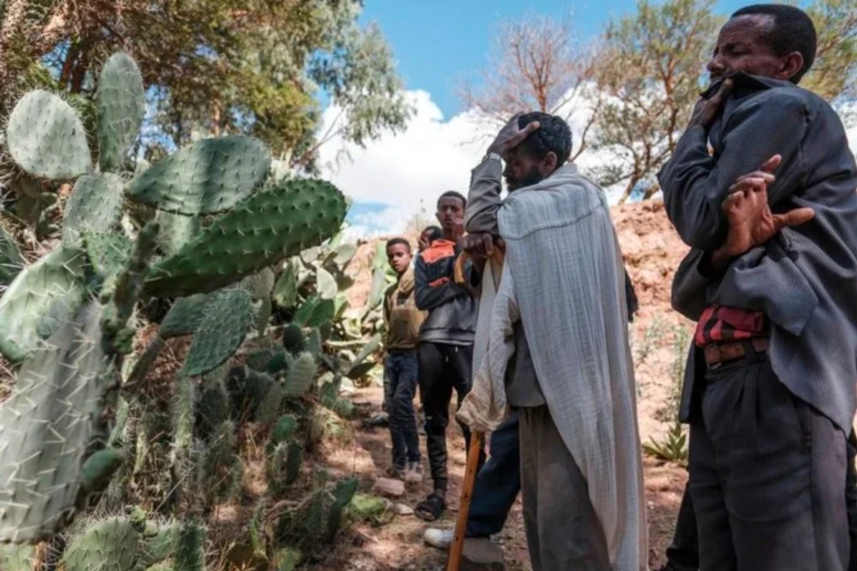 Des gens pleurent devant une fosse commune les victimes d'un massacre qui aurait été perpétré par des soldats érythréens voisins dans le village de Dengolat, au nord de Mekele, la capitale du Tigré, le 26 février 2021 (AFP)