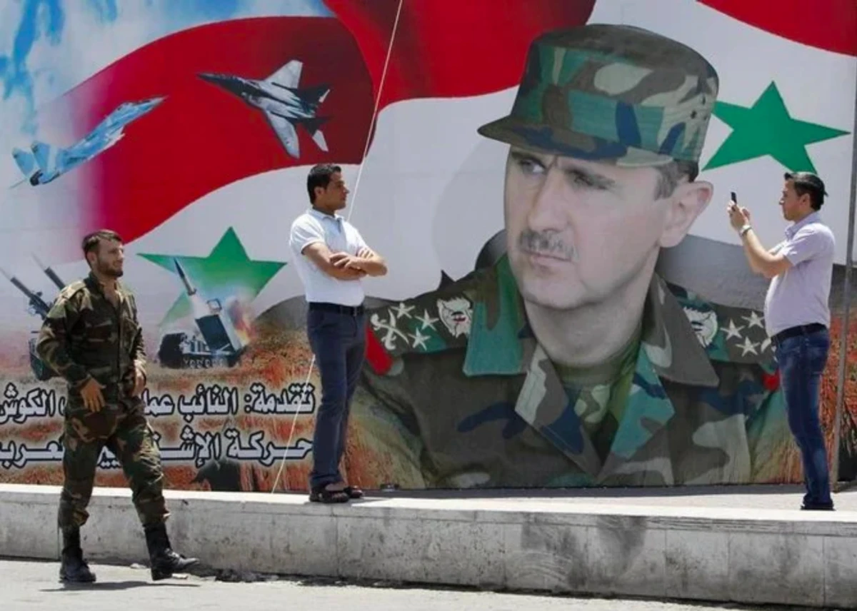 Un homme prend une photo de son ami devant une affiche du président syrien Bachar al-Assad sur la place des Omeyyades à Damas, le 16 mai 2014 (Reuters)