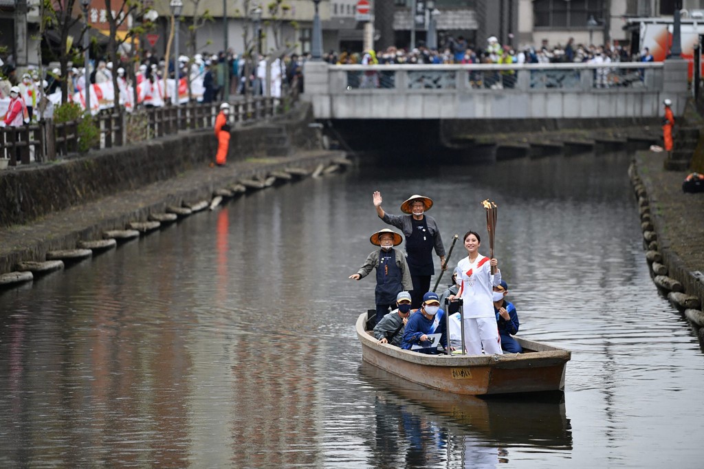 Cette photographie prise et publiée le 28 mars 2021 par Tokyo 2020 montre une Japonaise portant la torche olympique sur un bateau lors du relais de la flamme dans la ville orientale de Tochigi. HANDOUT / TOKYO 2020 / AFP
