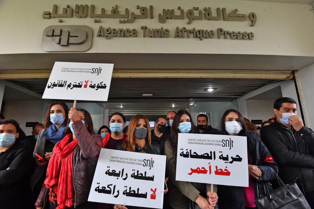 Les journalistes brandissent des pancartes indiquant en arabe (de droite à gauche) "la liberté de la presse est une ligne rouge", "le quatrième pouvoir ne se met pas à genoux" et "un gouvernement qui ne respecte pas la loi", alors qu'ils se rassemblent pour une manifestation à l'extérieur le siège de l'agence de presse nationale tunisienne Tunis Afrique Presse (TAP) dans la capitale le 15 avril 2021. FETHI BELAID / AFP