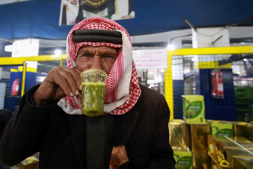 Un Jordanien goûte de l'huile d'olive fraîchement pressée dans un pressoir automatique à Mahis, à l'ouest de la capitale Amman, le 20 novembre 2020. (Khalil Mazraawi/AFP)