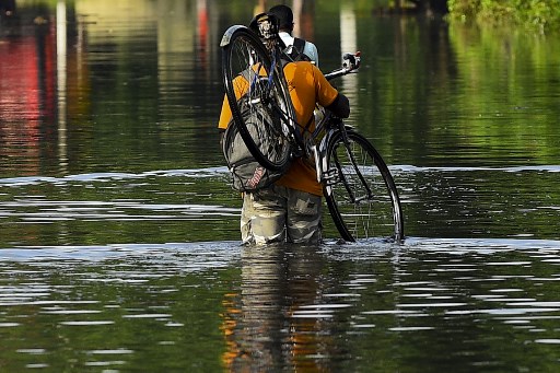 Un habitant porte son vélo alors qu'il marche dans les eaux de crue après de fortes pluies de mousson à Kelaniya, à la périphérie de Colombo, le 6 juin 2021 (Photo, AFP)