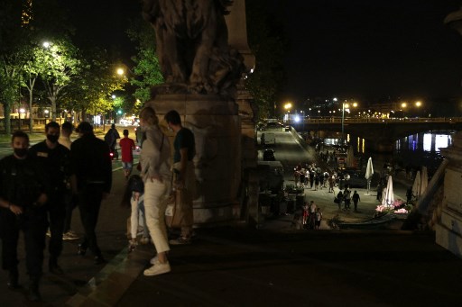 Des gens se tiennent sur les rives de la Seine après le couvre-feu Covid-19 de 23 heures, tôt le 12 juin 2021, après que des personnes se soient rassemblées à proximité, aux Invalides, pour une fête en plein air non autorisée