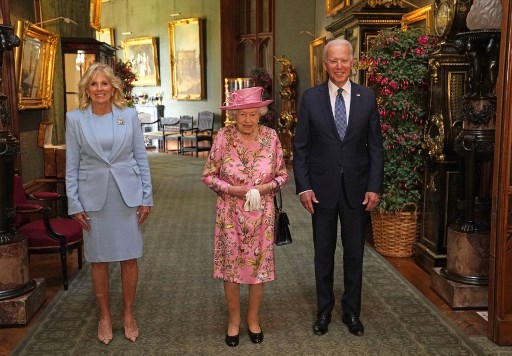 En robe à fleur et chapeau roses, la souveraine de 95 ans, encadrée par Joe Biden et sa femme Jill (Photo, AFP)