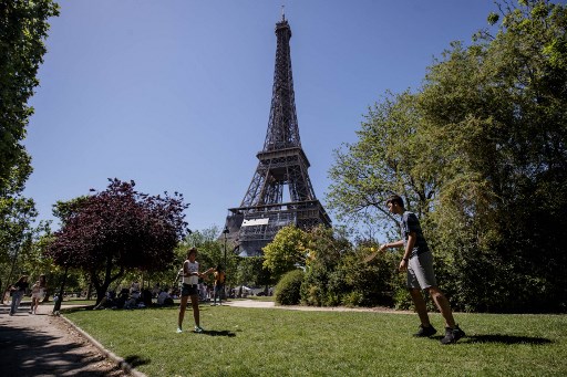 Des enfants jouent par un après-midi ensoleillé, dans le parc du Champs de Mars, alors que la Tour Eiffel est vue en arrière-plan, à Paris, le 13 juin 2021 (Photo, AFP)