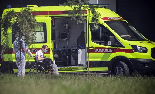 Des médecins escortent un homme dans un hôpital où des patients infectés par le nouveau coronavirus COVID-19 sont soignés dans la colonie de Kommunarka à l'extérieur de Moscou le 17 juin 2021.La Russie signale 14,057 nouveaux cas quotidiens de Covid-19 dont 6,195 à Moscou. (Alexandre Nemenov/AFP)