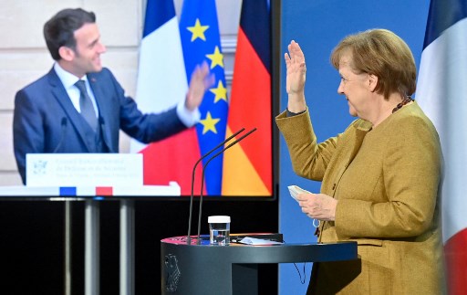 Dans cette photo d'archive prise le 5 février 2021, la chancelière allemande Angela Merkel et le président français Emmanuel Macron saluent à la fin d'une conférence de presse après les entretiens vidéo du Conseil de sécurité franco-allemand à Berlin. (John Macdougall / Pool / AFP)
