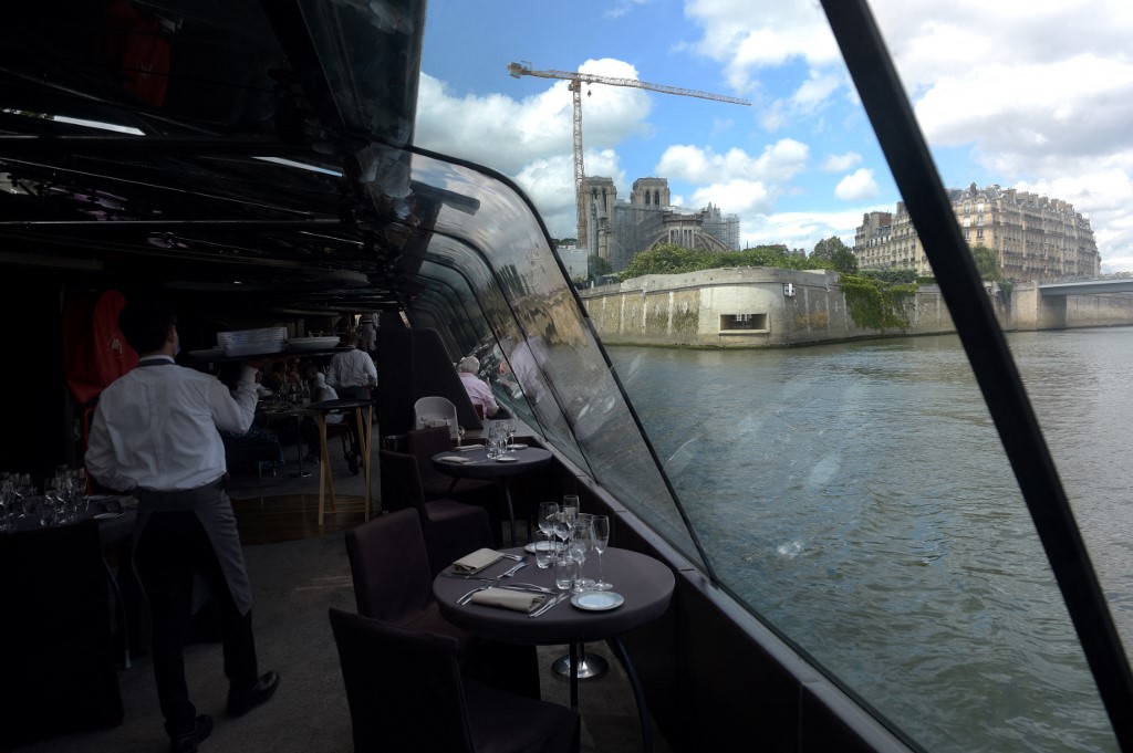 Les gens profitent d'une excursion en bateau-restaurant à bord d'un bateau des "Bateaux Parisiens" pour un déjeuner-croisière sur la Seine à Paris le 18 juin 2021.(AFP)