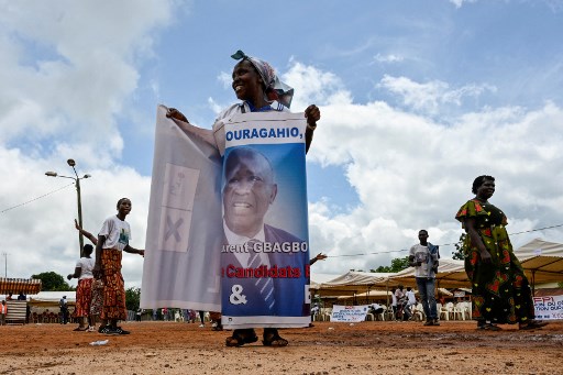 Une femme s'enveloppe d'une banderole à l'effigie de l'ancien président ivoirien Laurent Gbagbo avant son arrivée à Mama le 27 juin 2021 (Photo, AFP)