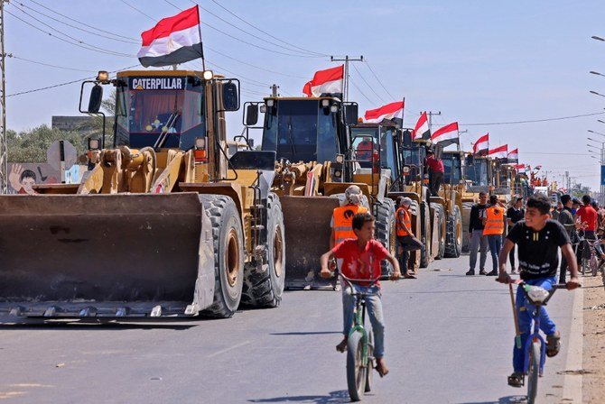 Des garçons palestiniens passent à vélo devant un convoi de bulldozers fournis par l’Égypte, alors qu’ils arrivent du côté palestinien du poste-frontière de Rafah entre l’Égypte et la bande de Gaza, le 4 juin 2021 (Photo, AFP)
