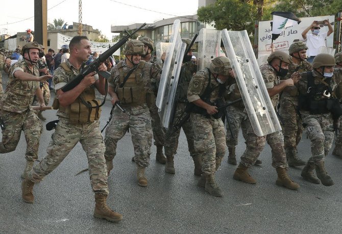Dans cette photo d'archive du 12 septembre 2020, un soldat de l'armée libanaise, à gauche, tire en l'air pour repousser les manifestants antigouvernementaux alors que d'autres soldats se protègent des pierres, lors d'une manifestation contre le président libanais Michel Aoun près du palais présidentiel , à Baabda à l'est de Beyrouth, au Liban (Fichier/AP