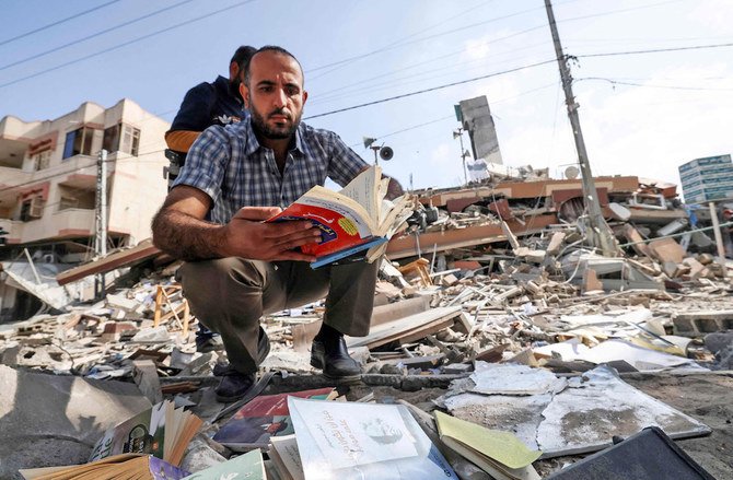 Un Palestinien feuillette un livre qu’il a trouvé dans les décombres de l’immeuble Kuhail, qui abritait la librairie Samir Mansour, dans la ville de Gaza (Photo, AFP)