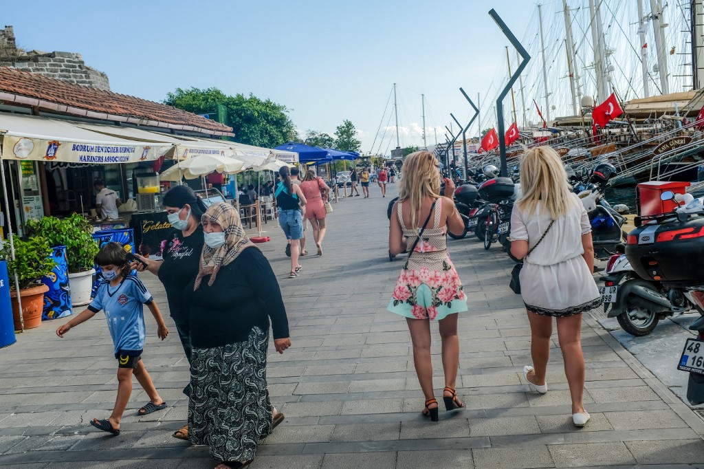 Des touristes ukrainiens (à droite) marchent à côté de Turcs à Bodrum, sur la mer Égée, dans le sud-ouest de la Turquie (AFP)