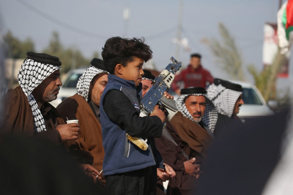 Un enfant irakien porte une fausse machine alors que des membres armés des clans de lèvent leurs armes.Les tribus irakiennes sont redevenues l'un des acteurs les plus puissants du sud rural et riche en pétrole (photo d'archives) (AFP)