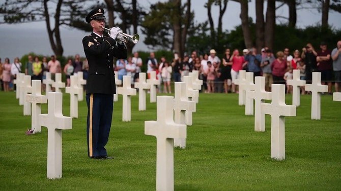 Un membre de la fanfare de l'armée américaine en Europe rend hommage aux soldats tombés au champ d'honneur, au cimetière américain en Normandie, lors du 75e anniversaire du jour J, en 2019. (YouTube)