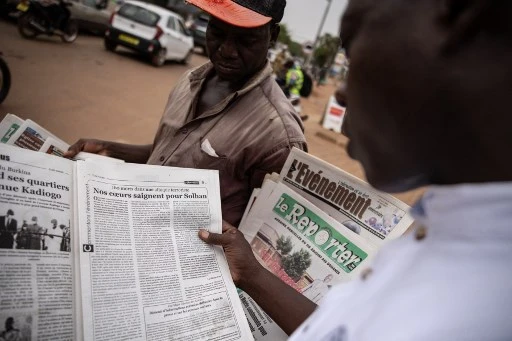 Un homme lit un article dans le journal L'Observateur Paalga à Ouagadougou le 7 juin 2021, sur les attentats survenus à Solhan (Photo, AFP)
