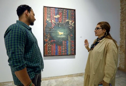 Un visiteur s'entretient avec l'artiste libyenne Elham el-Ferjani devant l'une de ses œuvres à la galerie Hamim de la ville orientale de Benghazi, le 14 juin 2021 (Photo, AFP)