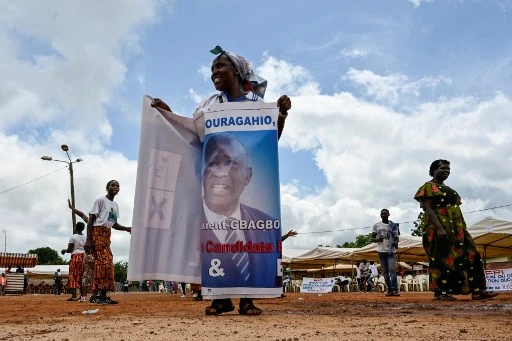 Une femme s'enveloppe d'une banderole à l'effigie de l'ancien président ivoirien Laurent Gbagbo avant son arrivée à Mama le 27 juin 2021 (Photo, AFP)