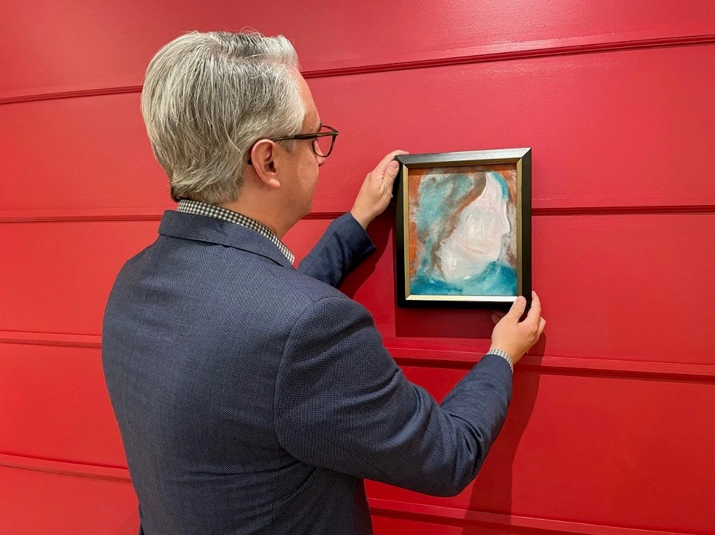 Une photo publiée le 15 juin 2021, avec l'aimable autorisation de la maison de vente aux enchères Cowley Abbott, montre le spécialiste de l'art canadien Rob Cowley regardant une peinture de l'icône de la pop britannique David Bowie. (AFP)