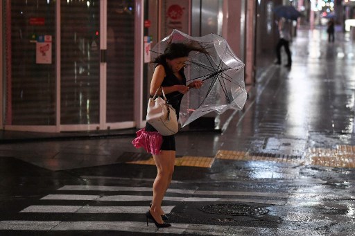 Une femme tient son parapluie alors que le vent grandit à Tokyo le 8 septembre 2019. (Charly Triballeau / AFP)