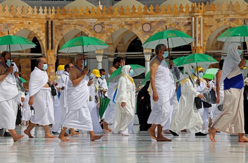 Des pèlerins tenant des parapluies pour se protéger de la chaleur arrivent à la Kaaba, le sanctuaire le plus saint de l'Islam, à la Grande mosquée de la ville sainte de La Mecque, au début de la saison du Hajj, le 17 juillet 2021. L'Arabie saoudite accueille un nouveau hajj réduit à partir du 17 juillet, seuls les résidents entièrement vaccinés contre le coronavirus étant autorisés. (Fayez Nureldine/AFP)