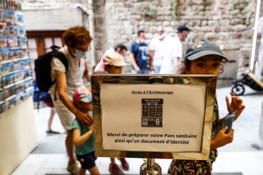 Panneau indiquant "Merci d'avoir préparé votre carte de santé ainsi qu'un document d'identité" à l'entrée d'une boutique de souvenirs au Mont-Saint-Michel, en Normandie. (Sameer Al-Doumy/AFP)