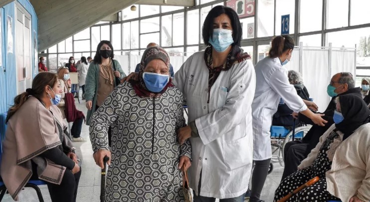 Une infirmière accompagne une femme âgée pour recevoir une dose du vaccin contre le coronavirus à la salle de sport El-Menzah à Tunis, le 12 avril 2021. (Photo d'archives FETHI BELAID / AFP)