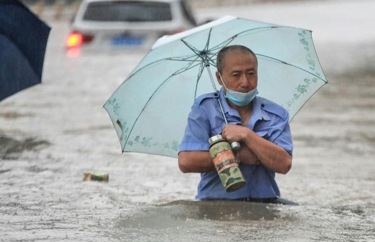 Un homme avance dans une rue inondée de Zhengzhou, placée en alerte rouge après des orages violents qui se sont abattus sur cette métropole du centre de la Chine, le 20 juillet 2021. Archives/AFP