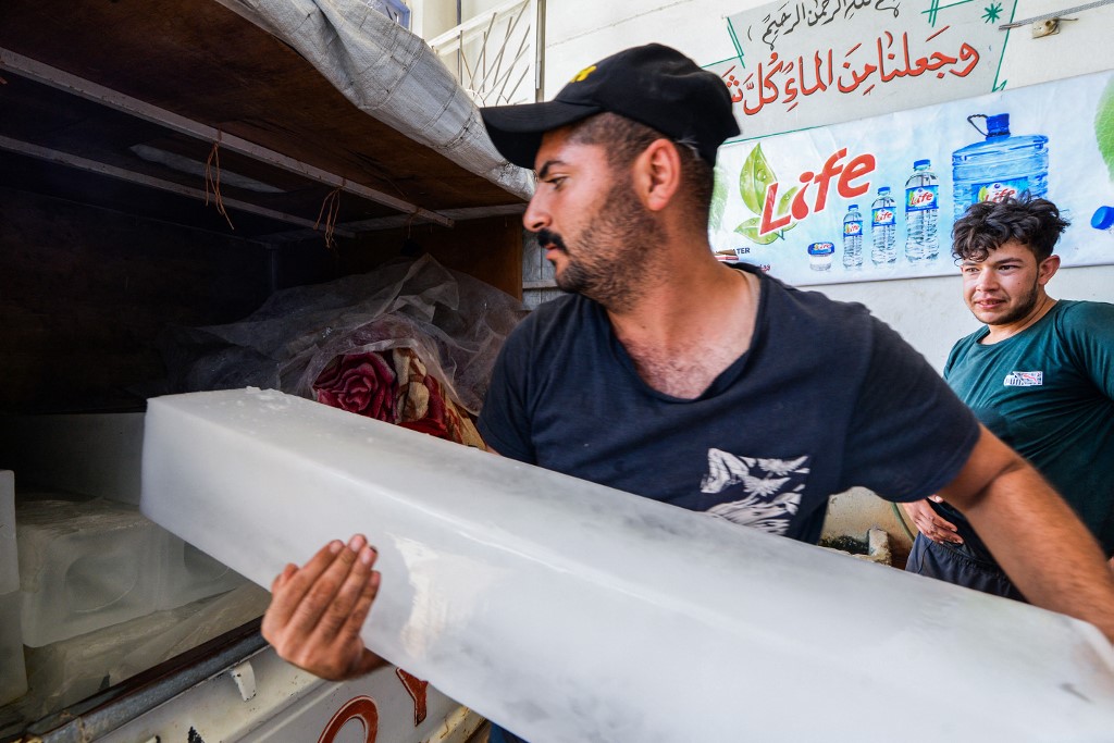 Un ouvrier irakien charge des blocs de glace dans la camionnette d'un client dans une usine de la ville de Mossoul, dans le nord du pays, sur fond de pannes de courant et de températures en hausse (AFP)