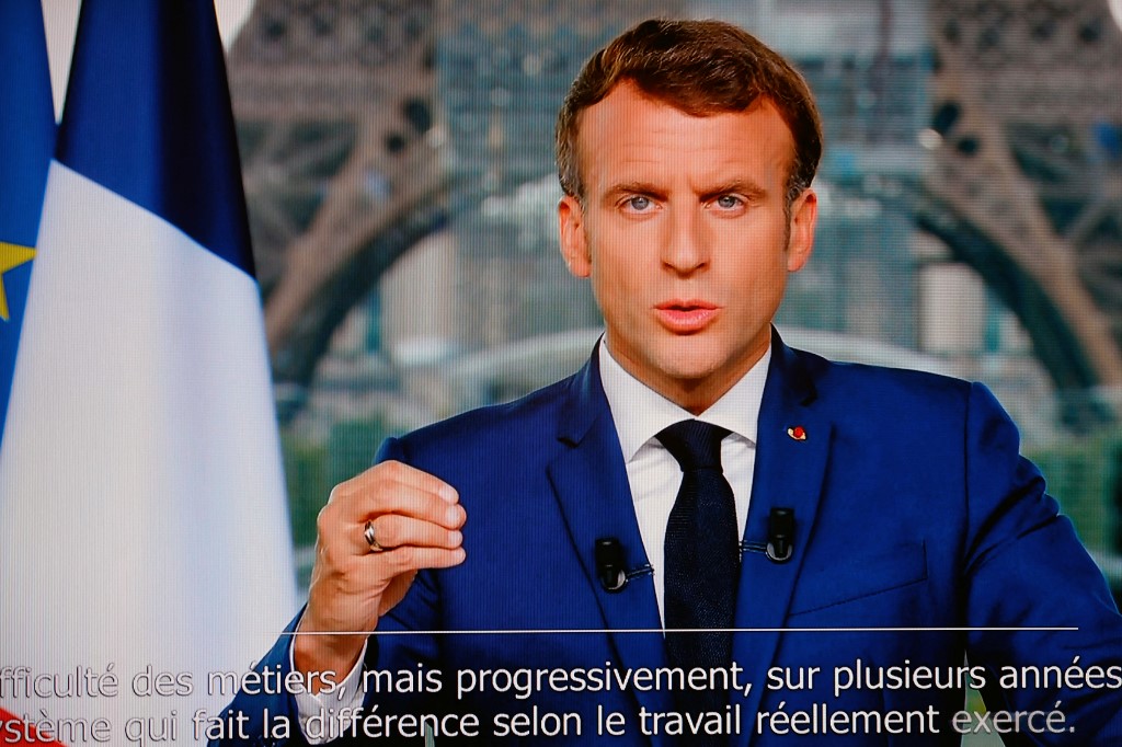 Le président français Emmanuel Macron est vu sur un écran de télévision alors qu'il s'exprime lors d'une allocution télévisée à la nation depuis le Grand Palais temporaire à Paris (AFP)