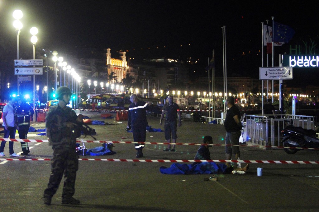 Dans cette photo d'archives prise le 15 juillet 2016, des soldats, des policiers et des pompiers marchent près de cadavres recouverts de draps bleus sur le front de mer de la Promenade des Anglais à Nice (AFP)
