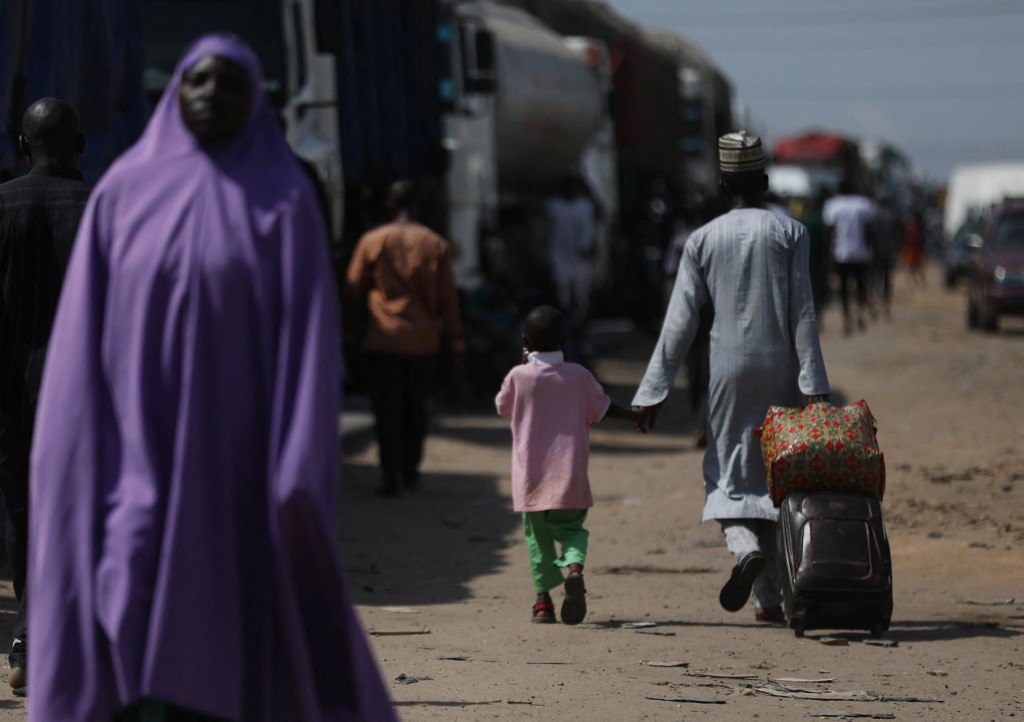 Un homme marche avec son fils alors que des habitants bloquent l'autoroute Kaduna-Abuja à Gauruka, au Nigeria, lors d'une manifestation contre les enlèvements incessants dans l'État du Niger (photo d'archives)(AFP)