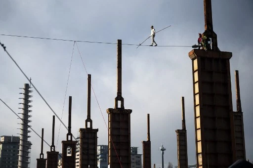 Le funambule italien Andrea Loreni sur une corde d'acier à 25 mètres de haut entre deux tours d'une usine du Parco Dora à Turin le 29 janvier 2021. (Marco Bertorello / AFP)