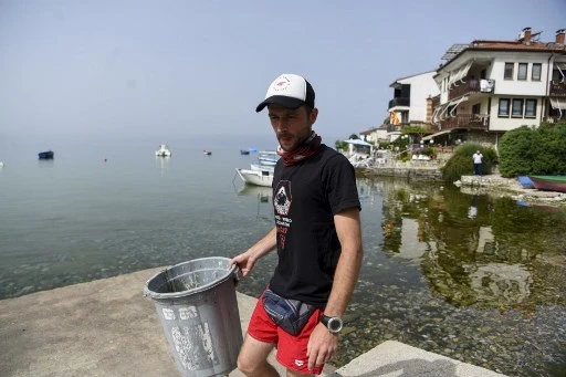 Le plongeur et archéologue Nikola Paskali collecte des déchets sur la plage de la vieille ville près des rives du lac d'Ohrid, au sud-ouest de la République de Macédoine du Nord, le 22 juin 2021. (Robert Atanasovski / AFP)