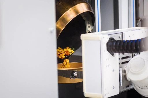 Une commande de pâtes arrive et le bras robotique entre en action au restaurant Roboeatz à Riga. Après cinq minutes de girations, une plaque chauffante est prête. Le café de Riga est conçu de manière à ce que les clients puissent observer le bras robotisé au travail. Une application Roboeatz permet aux clients de commander et de payer leur plat avant de le récupérer au café. (Gints Ivuskans / AFP)