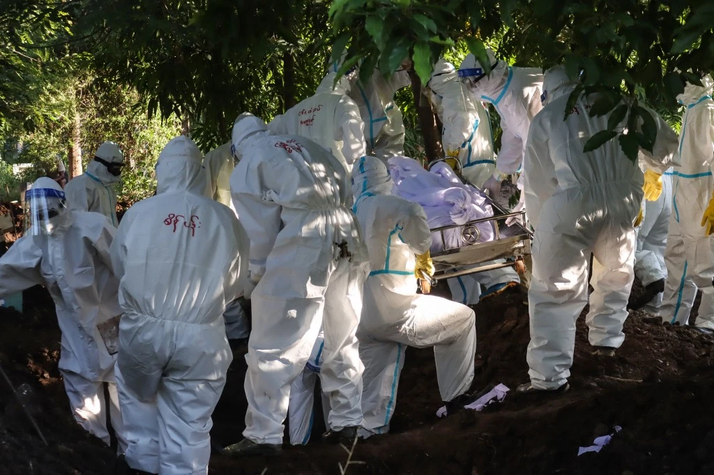 Des volontaires en combinaison sanitaires s'apprêtant à enterrer un birman décédé des suites du coronavirus. STR / AFP