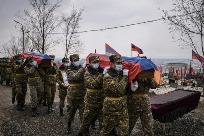 Des soldats arméniens transportant des cercueils de leurs confrères tués lors de la bataille du Nagorny-Karabakh, le 2 mars 2021 dans un cimetière à Erevan. Archives/AFP