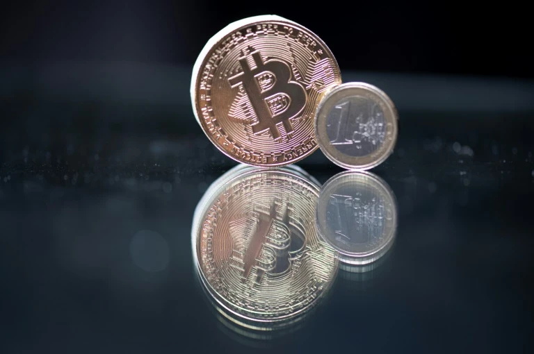 Immitation d'un bitcoin à côté d'une pièce d'un euro, à Paris, le 26 avril 2021 (AFP/Archives - Martin BUREAU