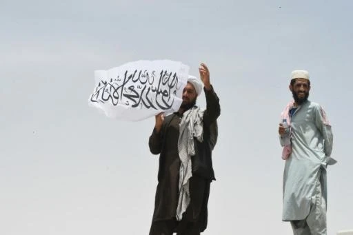 Un homme tient le drapeau taliban au côté afghan du point de passage de Chaman, le 17 juillet 2021 à la frontière avec le Pakistan. Archives AFP
