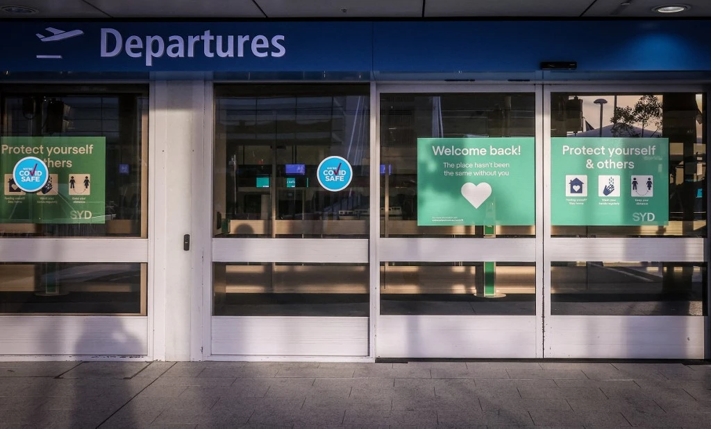 Cette photo montre des panneaux relatifs au nouveau coronavirus COVID-19 affichés à l'entrée de la zone des départs de l'aéroport international de Sydney (photo d'archives) (AFP)