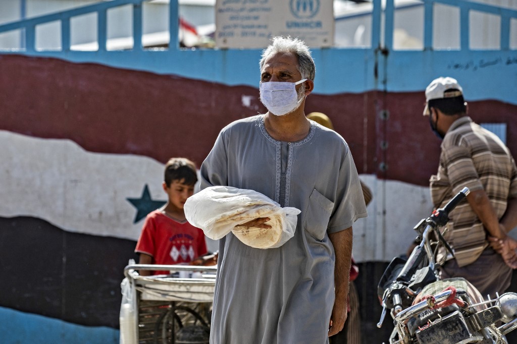 Un Syrien porte un sac de pain sur un marché de la ville de Qamishli, dans le nord-est de la Syrie (photo d'archives ) (AFP)