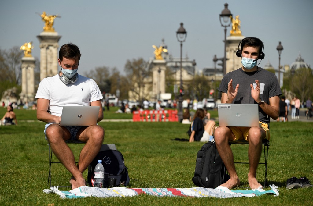 Deux hommes travaillent sur leur ordinateur en teletravail par une journée de printemps ensoleillée au milieu de la pandémie de coronavirus devant l'hôtel des Invalides à Paris (photo d'archives) (AFP)