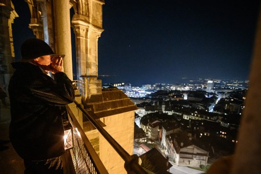 Veilleur de nuit de la cathédrale de Lausanne, Renato Haeusler crie l'heure précédant la sonnerie manuelle de la cloche de secours "La Clémence" de 3600 kg dans le clocher de la cathédrale, fin 27 mars 2020 à Lausanne, en pleine propagation du COVID-19 ( coronavirus nouveau). (Fabrice Coffrini/AFP)