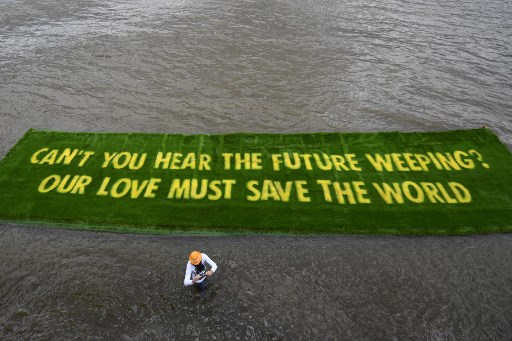 Un message sur un tapis d'herbe vive flotte sur la Tamise dans le centre de Londres le 25 juin 2021. Il invite les gouvernements à agir rapidement, dans la perspective de la COP26. (Daniel Leal-Olivas/AFP)