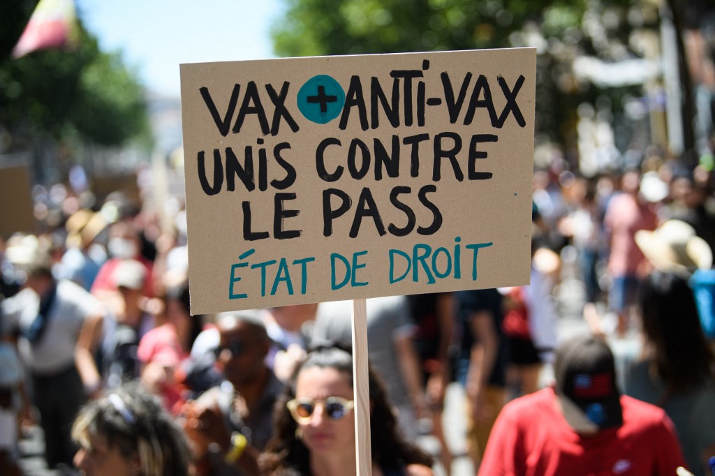 Un manifestant tient une banderole "Vax et anti-vax sont unis contre le Pass; Etat de droit" lors d'une manifestation à Marseille le 17 juillet 2021 (AFP)
