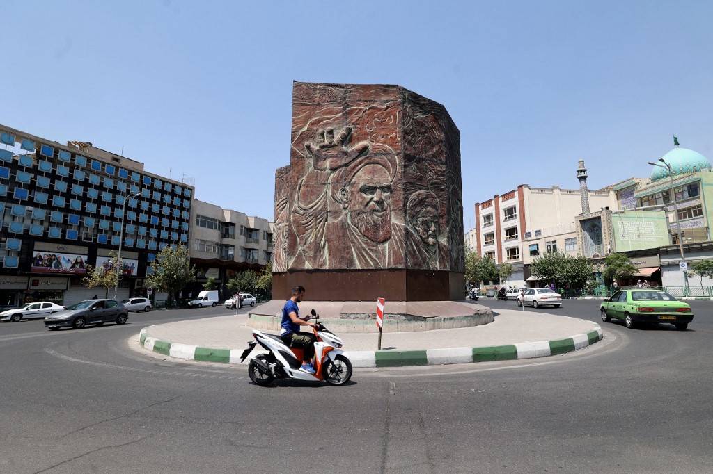 Un Iranien roule à moto sur la place Enghelab, dans le centre de la capitale Téhéran, le 20 juillet 2021, alors que les autorités renforcent les restrictions dans le cadre de la pandémie de COVID-19. (ATTA KENARE / AFP)
