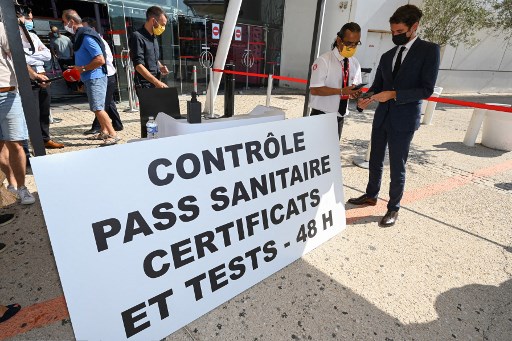 Le porte-parole du secrétaire d'État et du gouvernement français, Gabriel Attal (à droite), montre son « pass sanitaire » à un responsable alors qu'il visite le cinéma Gaumont Multiplex Odyséum à Montpellier, dans le sud de la France, le 29 juillet 2021. (Pascal Guyot/AFP)
