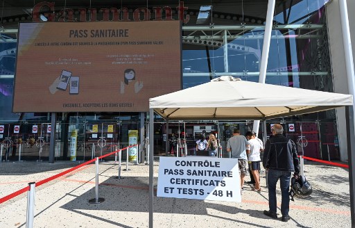Les visiteurs présentent leur pass sanitaire à un responsable à l'entrée du cinéma Gaumont Multiplex Odyséum à Montpellier, dans le sud de la France, le 29 juillet 2021. (Pascal Guyot/AFP)