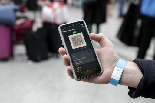 Un passager portant un bracelet bleu montre son pass sanitaire Covid-19 sur un téléphone portable à la gare de Lyon à Paris le 9 août 2021. (Geoffroy van der Hasselt/AFP)