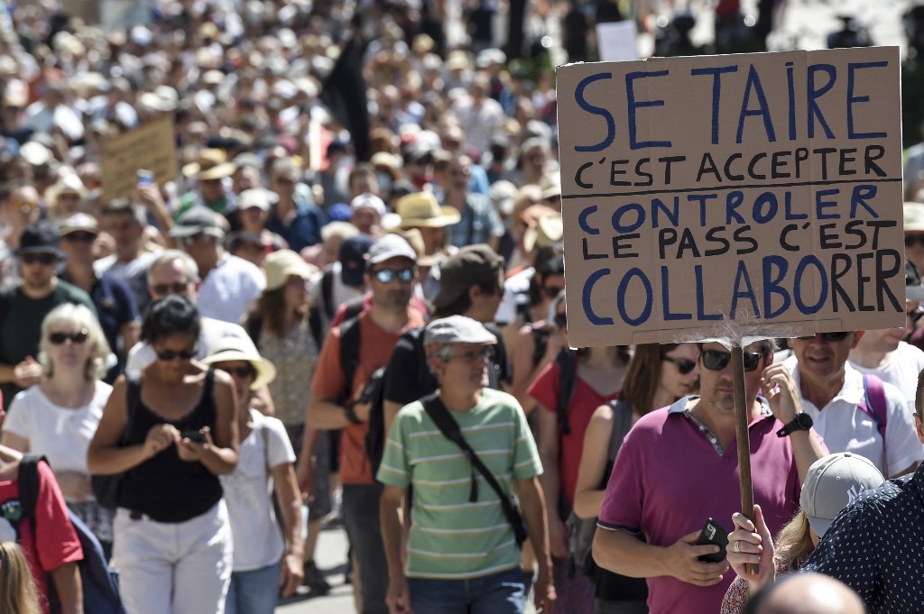 Un manifestant tient une pancarte sur laquelle on peut lire "Se taire, c'est accepter. Contrôler, c'est collaborer" lors d'une journée nationale de protestation contre le vaccin obligatoire Covid-19 pour certains travailleurs, et l'utilisation obligatoire du pass santé demandé par le gouvernement français pour accéder à la plupart des espaces publics, à Nantes, dans l'ouest de la France, le 14 août 2021. (Sebastien SALOM-GOMIS / AFP)